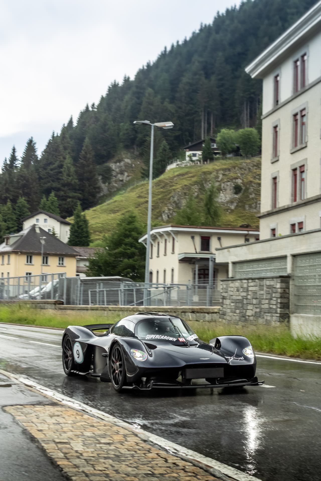 Aston Martin Valkyrie noire de face sur route mouillée
