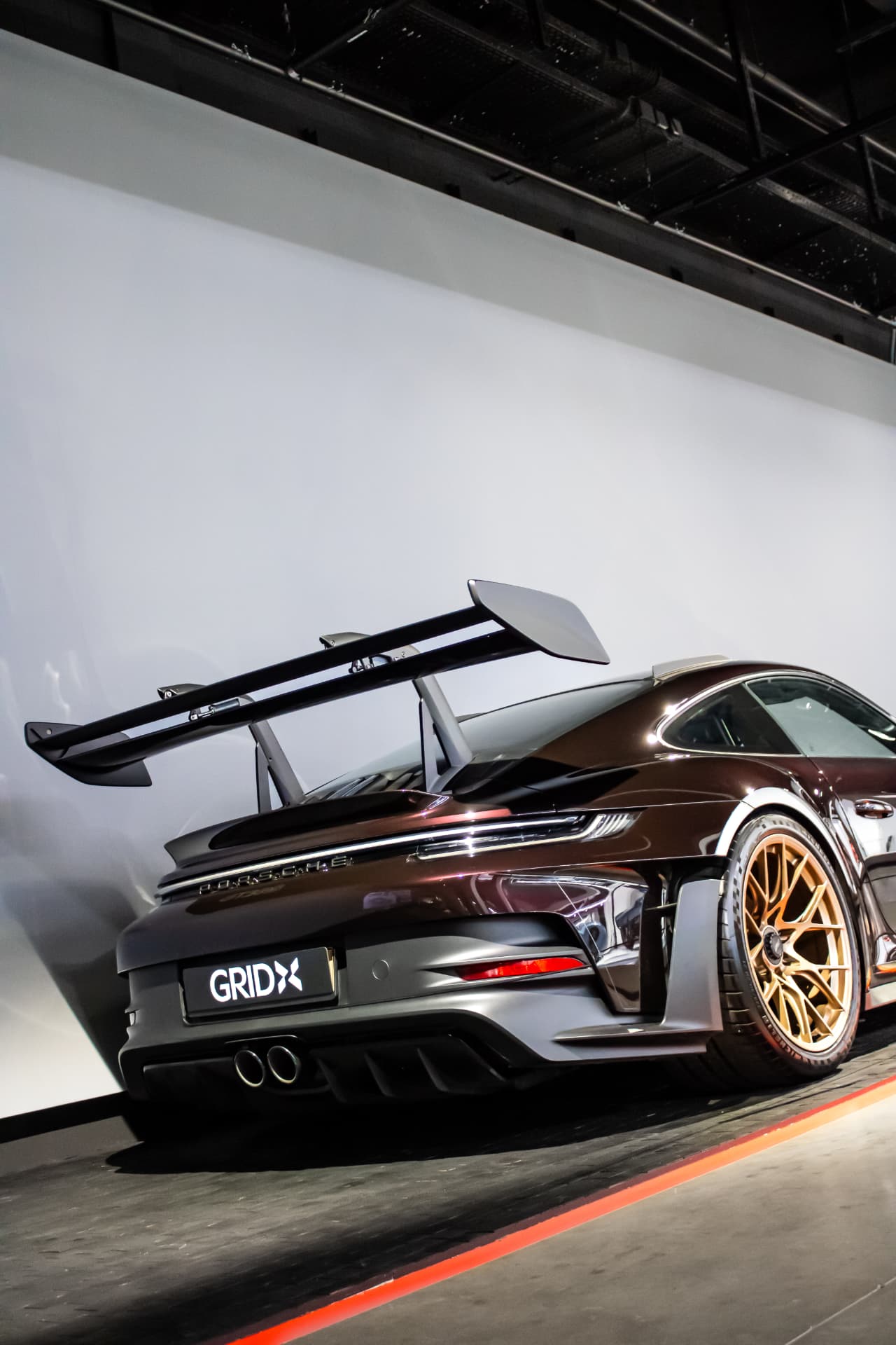 Porsche 992 GT3 RS bordeaux de trois-quarts arrière à GRID X