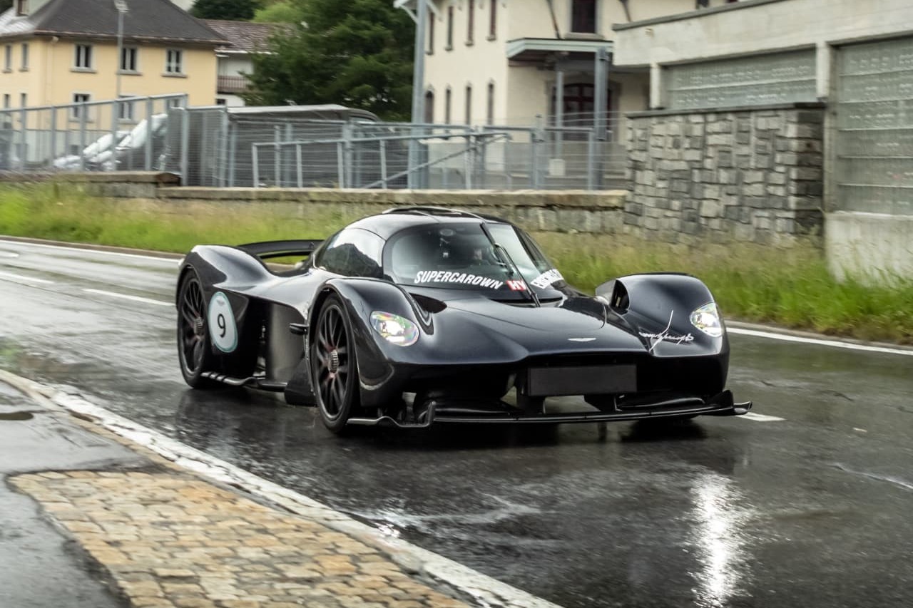 Aston Martin Valkyrie noire de face sur route mouillée à Andermatt